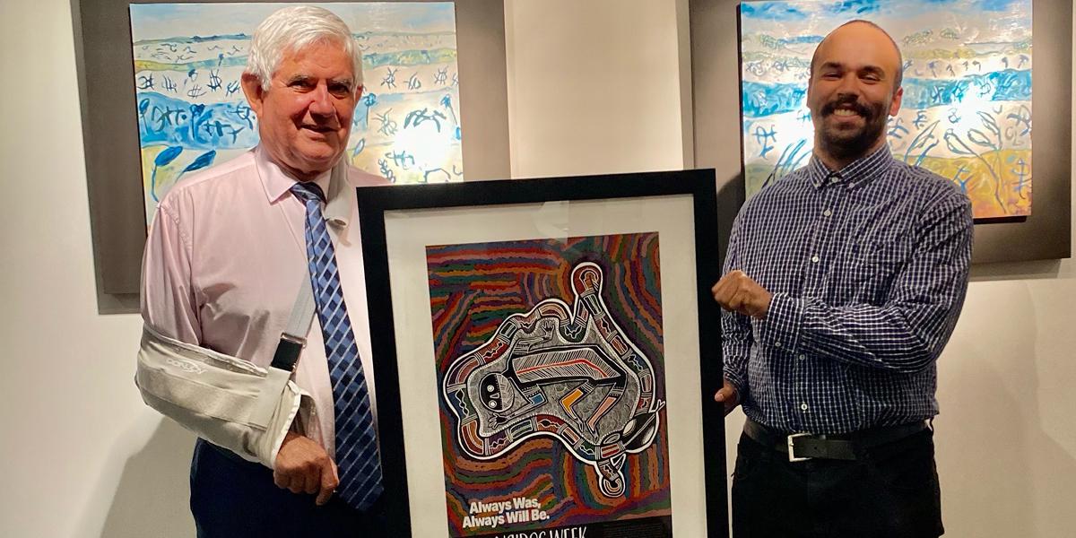 The Hon Ken Wyatt AM MP holding the 2020 NAIDOC Poster with the artist, Tyrown Waigana
