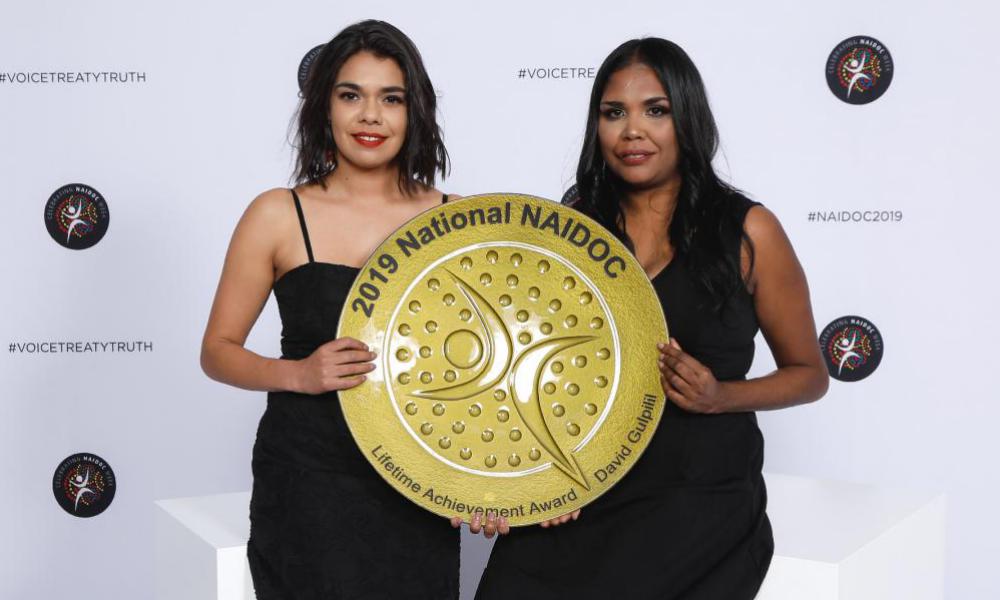 Two women hole a trophy '2019 National NAIDOC