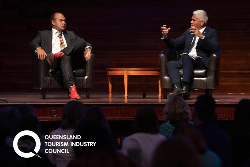 Two men talk on a stage