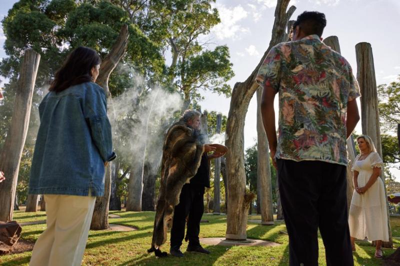 People stand watching a smoking ceremony
