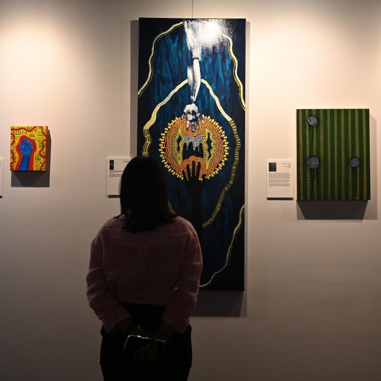 A person looks up at an artwork on the wall