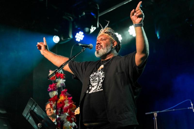 a man holds his arms out wide on stage