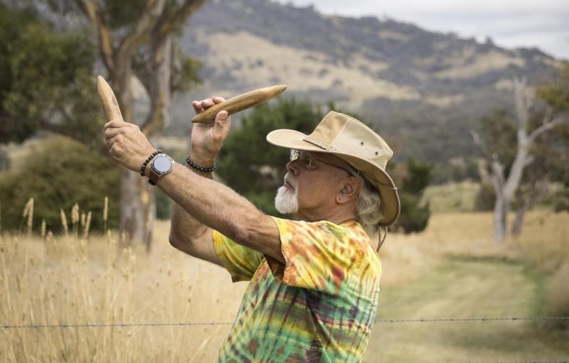 a man beats sticks above his head