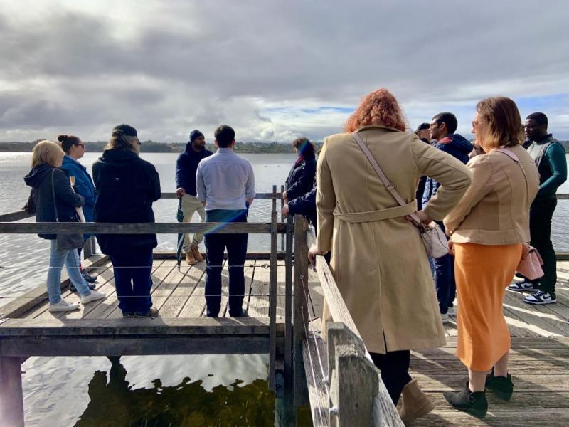 people stand on a dock by the lake