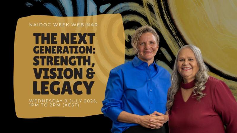 Two people stand in front of a NAIDOC poster