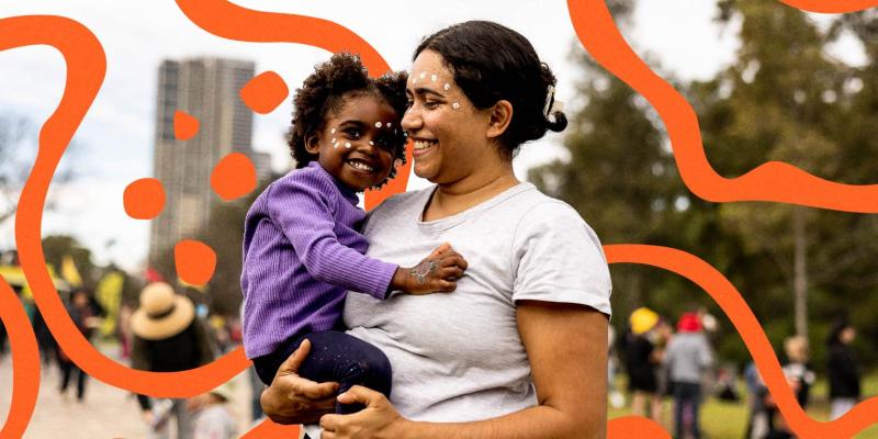 A mother holds her child walking past a colourful display