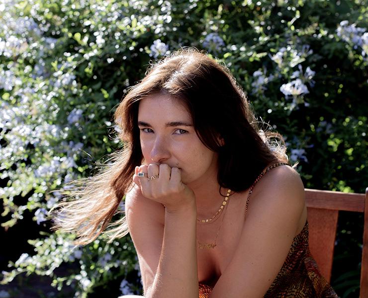 A lady sits in a chair in front of a garden