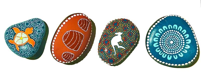Four massage stones with artwork on each