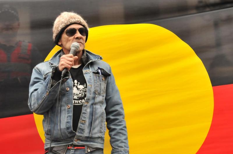 Robbie Thorpe in front of an Aboriginal flag