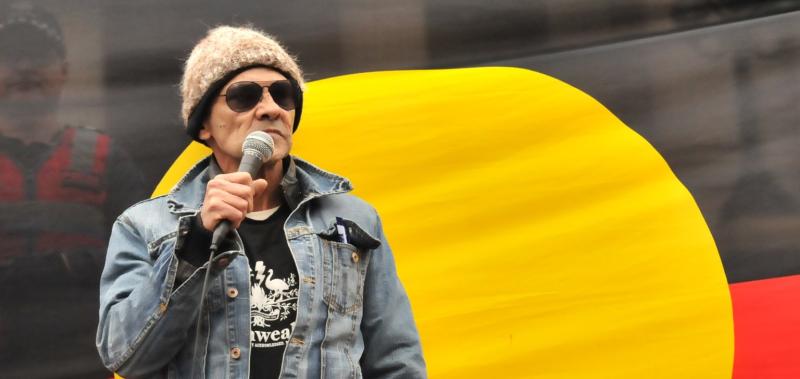 Robbie in front of an Aboriginal flag