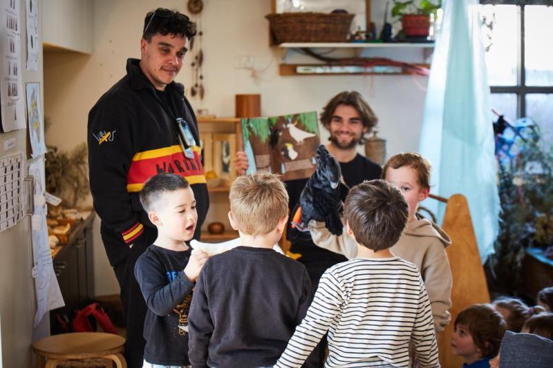 A man helps kids with art