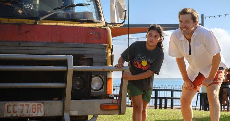 Two people looking at the front of a truck