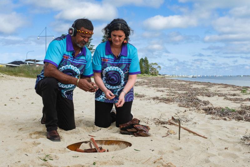 Two people lighting a fire on the beach