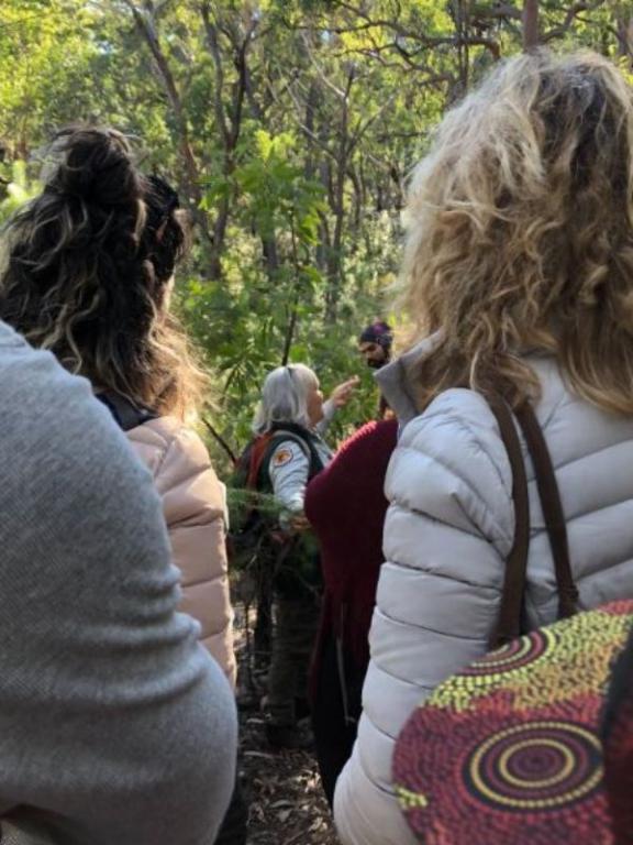 Aboriginal Discovery Ranger with participants looking on.